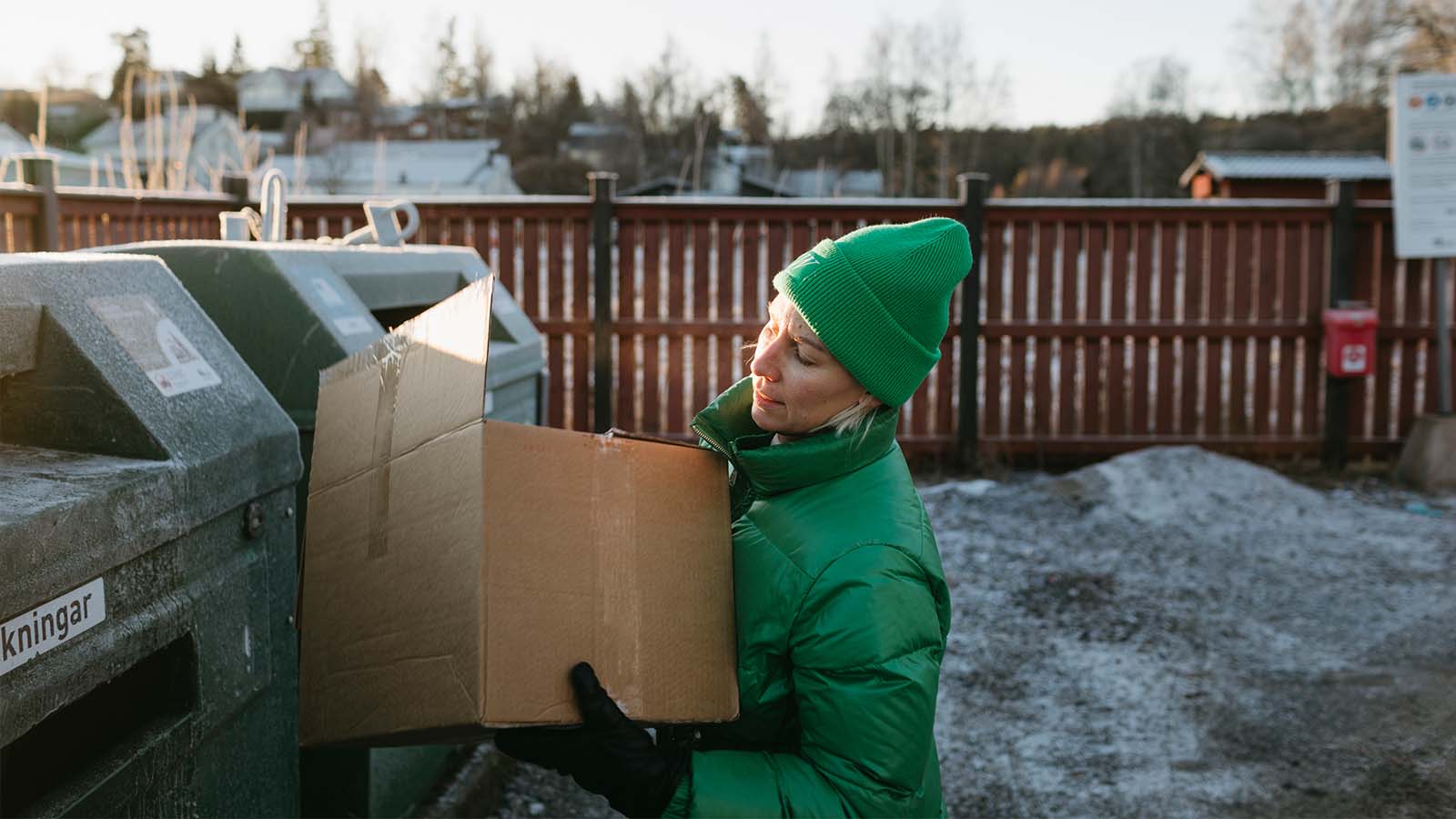 en kvinna står framför en återvinningsstation